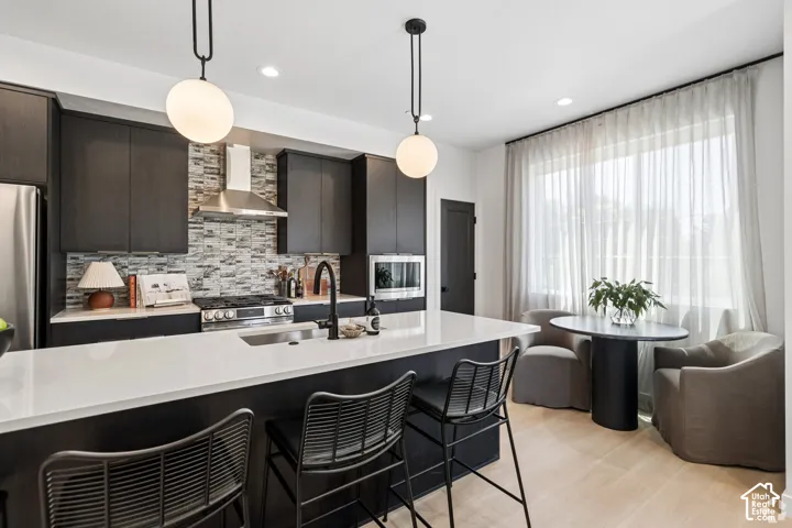 Kitchen featuring flat-panel cabinetry, quartz countertops, a stone-tile backsplash, stainless steel appliances, and dual globe pendant lighting