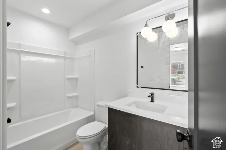Bathroom featuring a vanity with a white countertop, integrated rectangular sink, matte black faucet, framed mirror, and a tub-shower combination with surround