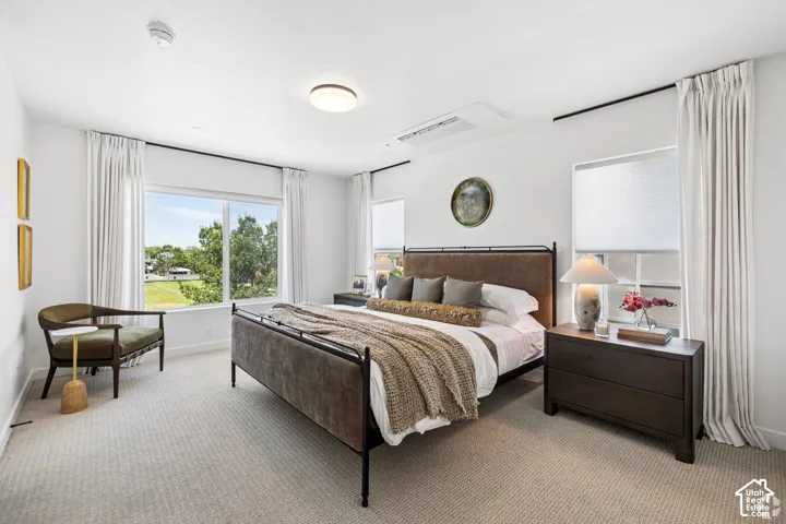Neutral-toned carpeting, oversized windows, and ceiling-mounted climate control unit