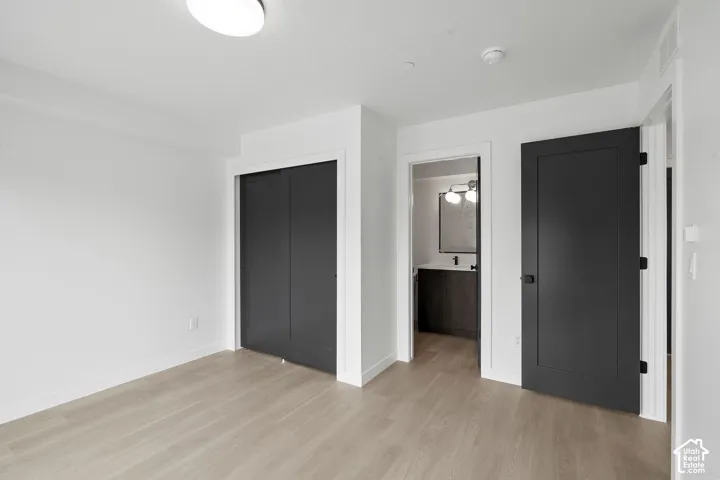 Neutral-toned interior featuring wood-finish flooring, matte black interior doors, a sliding-door closet, and overhead flush-mount lighting