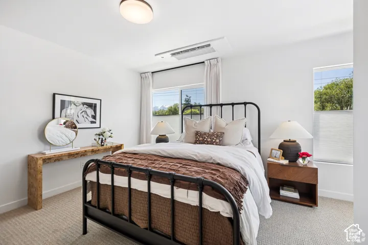 Bedroom featuring textured carpeting, dual-pane windows with integrated blinds, and recessed ceiling HVAC unit