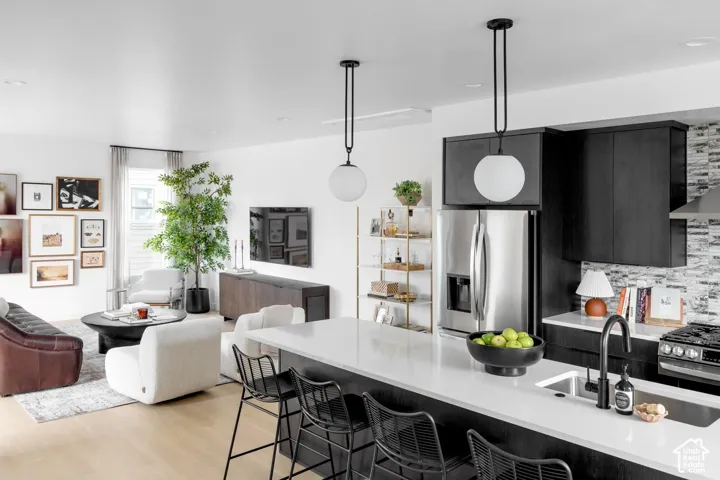 Kitchen featuring a central island with a solid surface countertop, matte black faucet, integrated stainless steel appliances, dark wood cabinetry, and dual globe pendant lighting