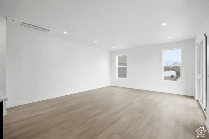 Neutral-toned interior featuring wood-finish flooring, recessed lighting, double-pane windows, and a sliding glass door