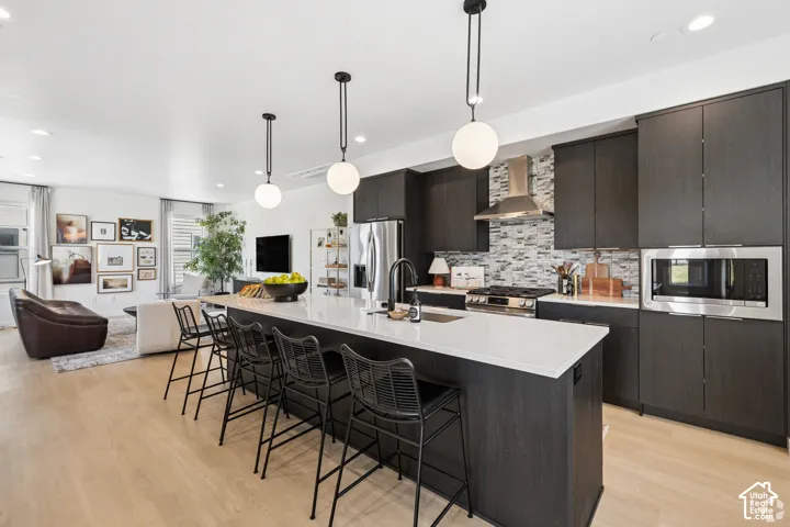Kitchen featuring dark cabinetry, quartz countertops, a textured tile backsplash, stainless steel appliances, and spherical pendant lighting
