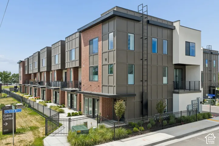 Modern multi-story exterior featuring brick and panel siding, metal balconies with cable railings, and attached exterior ladders