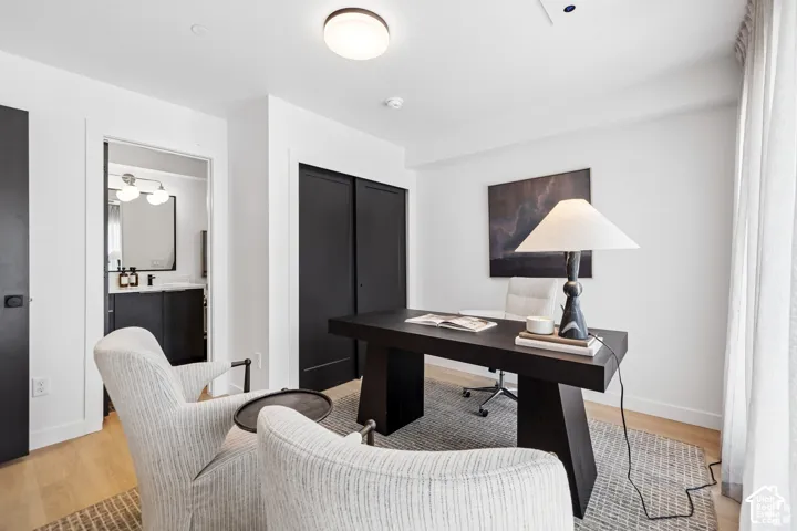 Neutral interior space featuring wood-finish flooring, matte black sliding closet doors, a neutral color palette, and a minimalist flush-mount ceiling light fixture