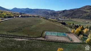 Expansive acreage featuring a fenced multi-sport court and mountain backdrop