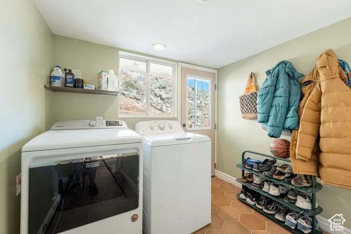 Laundry room featuring terracotta hexagonal tile flooring, a single-lite exterior door, a dual-pane window, and fixed wall shelving