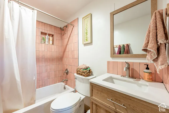 Bathroom featuring a wood-finish vanity with a white countertop, integral sink, brushed-metal fixtures, and a recessed shower niche with vertically-oriented wall tiling