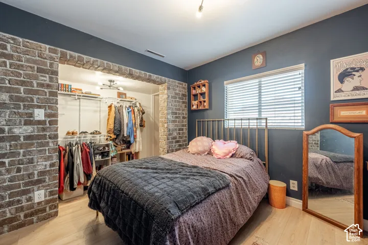 Exposed brick architectural archway, wood-finish flooring, and built-in closet organization system