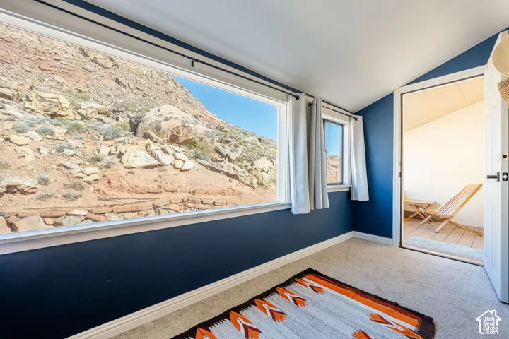 Expansive picture window showcasing natural rock formation scenery, carpeted flooring, and exterior door access