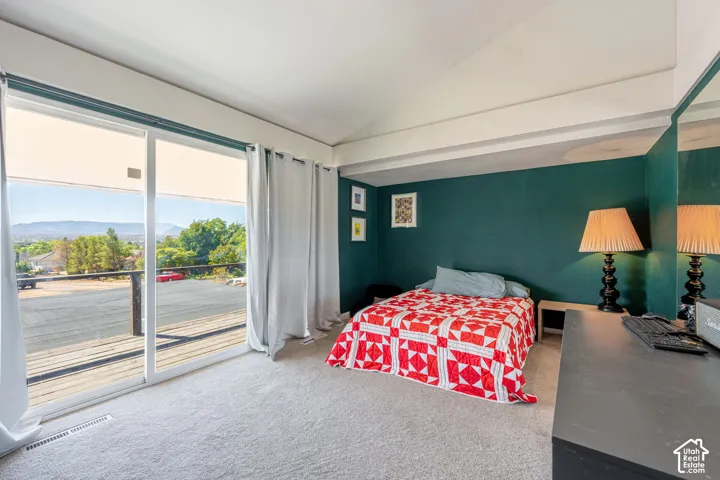 Vaulted ceiling, sliding glass doors providing outdoor access, and neutral carpeting