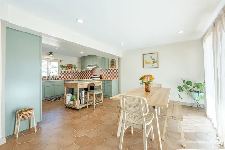 Kitchen featuring sage green cabinetry, a checkerboard tile backsplash, and hexagonal floor tile throughout