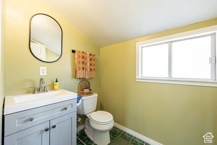 Grey vanity with an integrated basin, arched mirror, dual-pane horizontal sliding window, and patterned tile flooring