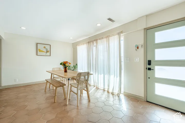 Hexagonal terracotta tile flooring, recessed ceiling lighting, and a multi-panel door with glass inserts