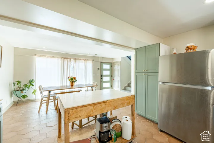 Hexagonal tile flooring, full-height sage green cabinetry, stainless steel refrigerator, and recessed ceiling lighting