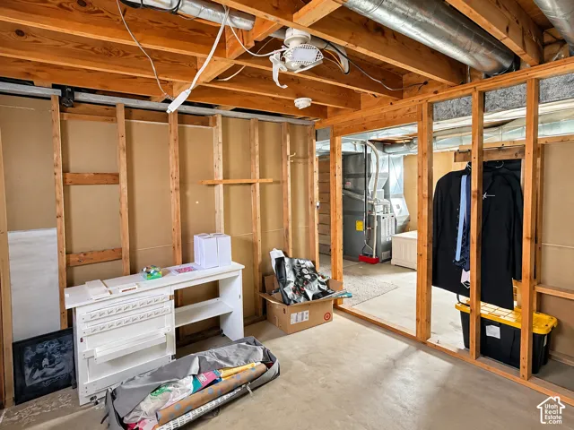 Unfinished basement featuring exposed wood-stud framing, exposed ceiling joists, concrete flooring, and a mechanical furnace system