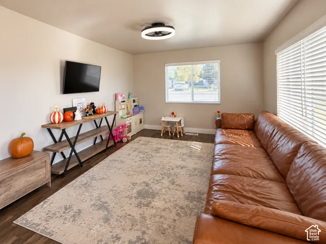 Wood-finish flooring, neutral wall tones, large window with horizontal blinds, and a modern circular flush-mount ceiling fixture