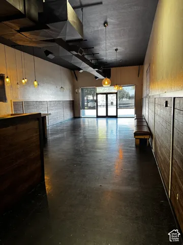 Open-concept interior horizontal wood-panel wainscoting, exposed ductwork, and suspended pendant lighting
