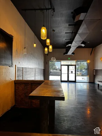 Commercial space featuring a custom wooden bar, industrial-style exposed ductwork, pendant lighting with glass-jar fixtures, and wood-plank wall wainscoting.