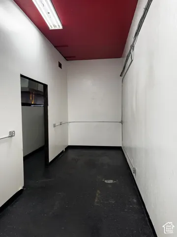 Industrial-style space featuring high-contrast finishes, dark resilient flooring, exposed electrical conduit, and a linear overhead lighting fixture