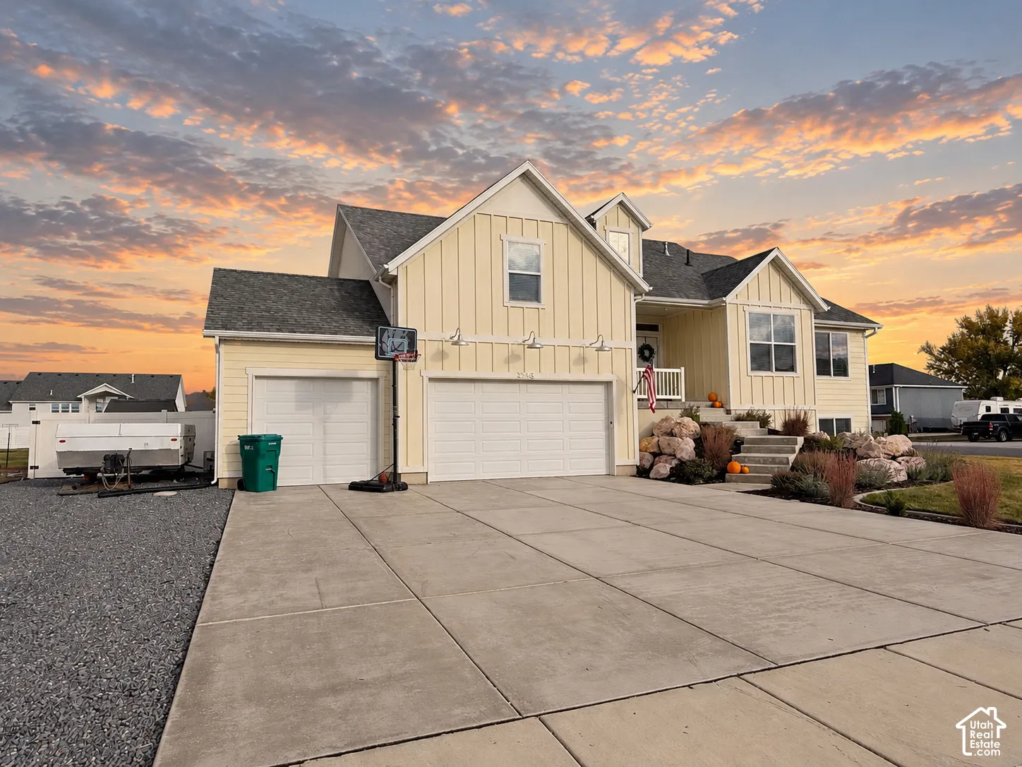 Board-and-batten siding exterior, asphalt shingle roof, multi-car garage, concrete driveway, and stone landscaping accents