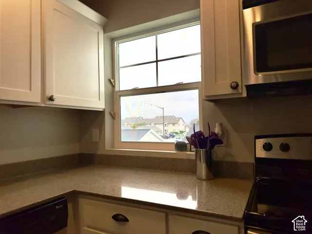 Kitchen featuring white cabinetry, solid-surface countertops, integrated microwave, and a window with exterior mullions