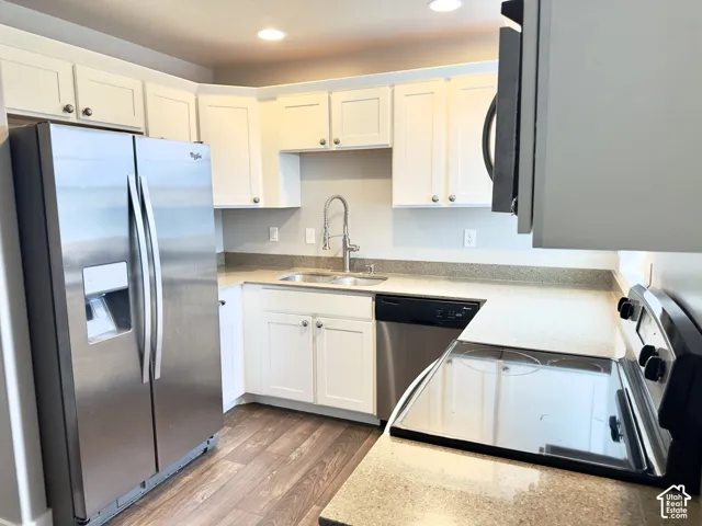 Kitchen featuring white cabinetry, stone-finish countertops, stainless steel appliances, wood-finish flooring, and a gooseneck faucet