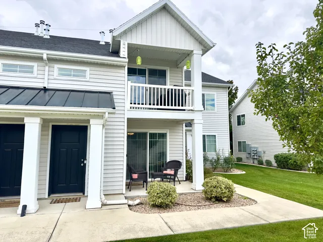 Exterior featuring horizontal lap siding, a metal shed roof, second-story balcony with white railing, covered ground-level patio, and square columns