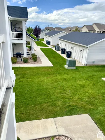 Exterior view featuring multi-unit structures with light-toned siding, dark shingled roofing, concrete walkways, and manicured green space