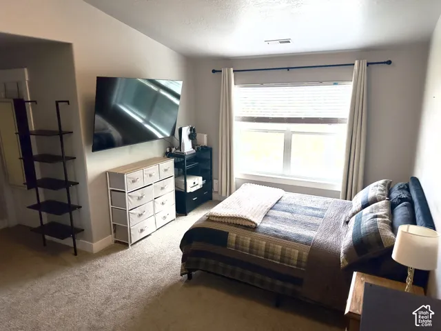 Neutral-toned interior featuring wall-to-wall carpeting and a large window with blind treatments