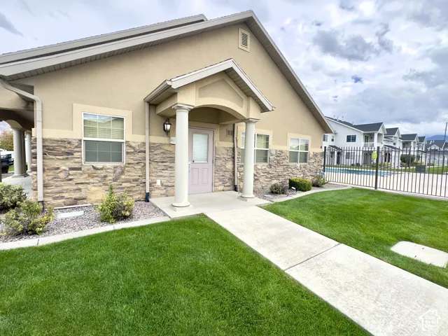 Exterior facade featuring stone veneer, stucco siding, arched entryway with dual columns, and a concrete walkway