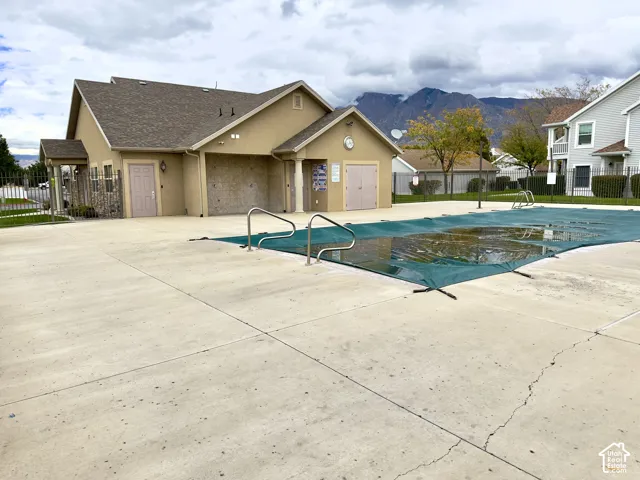 Community clubhouse featuring a swimming pool, concrete pool deck, and mountain backdrop