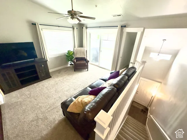 Vaulted ceilings, sliding glass door, ceiling fan with light fixture, carpeted flooring, and white wooden railing