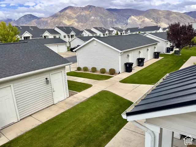 Exterior featuring horizontal siding, asphalt shingle roofing, concrete walkways, manicured lawn areas, and prominent mountain backdrop