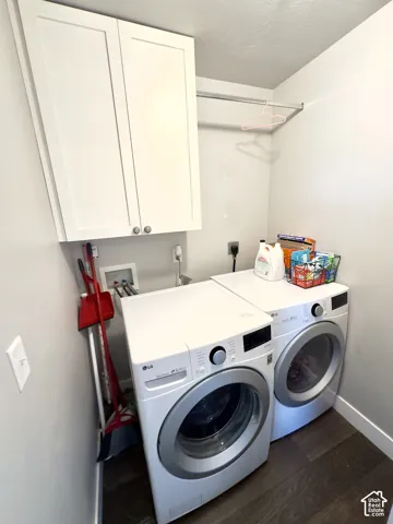 Laundry area featuring white Shaker-style wall cabinetry, a metal hanging rod, and dark wood-finish flooring