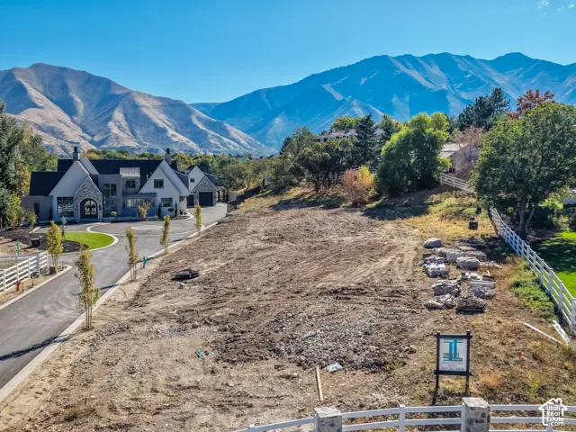 Expansive lot with mountain backdrop and white fencing