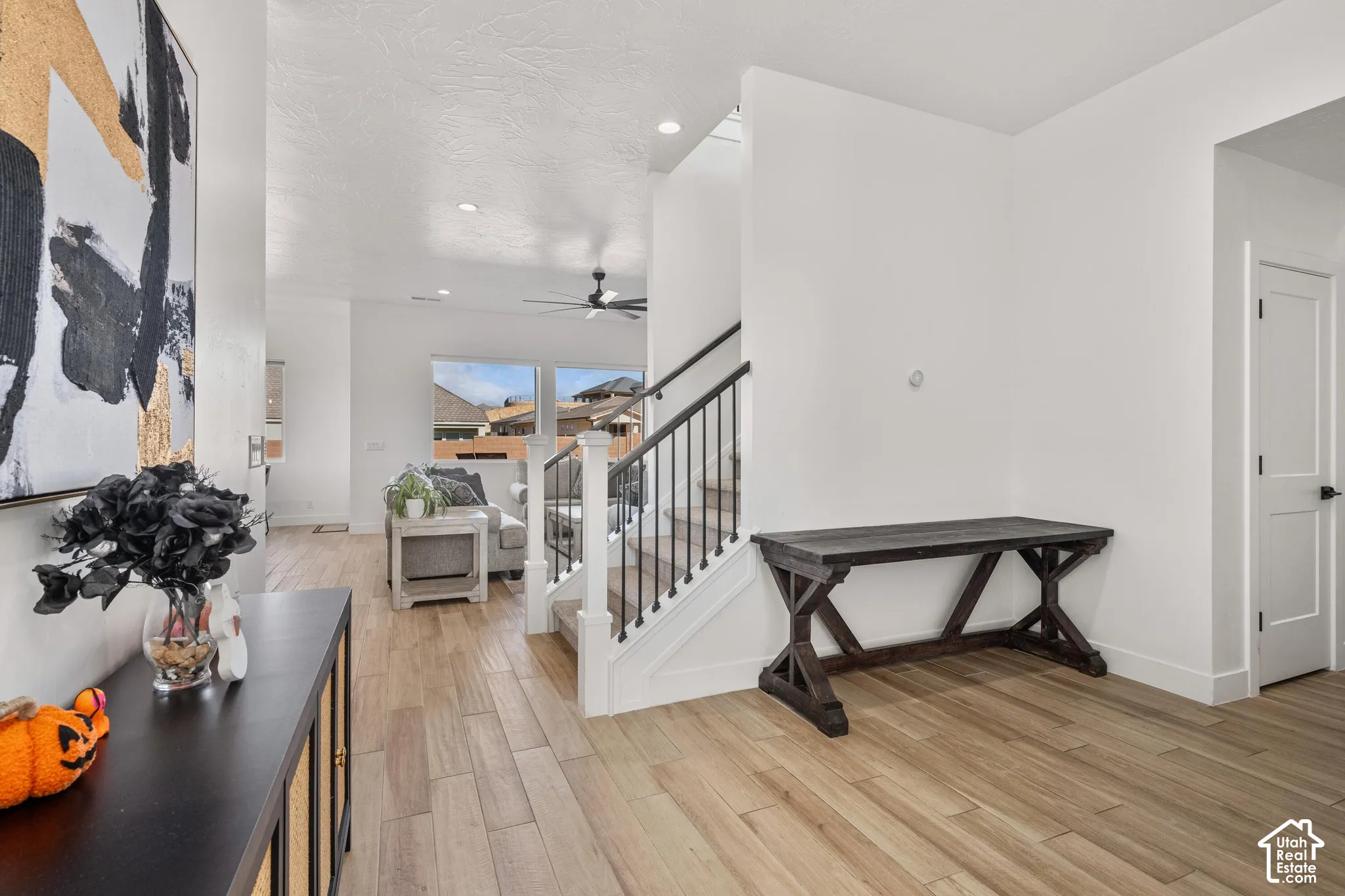 Interior featuring wood-finish flooring, recessed lighting, and a staircase with a white post-and-rail system with metal balusters