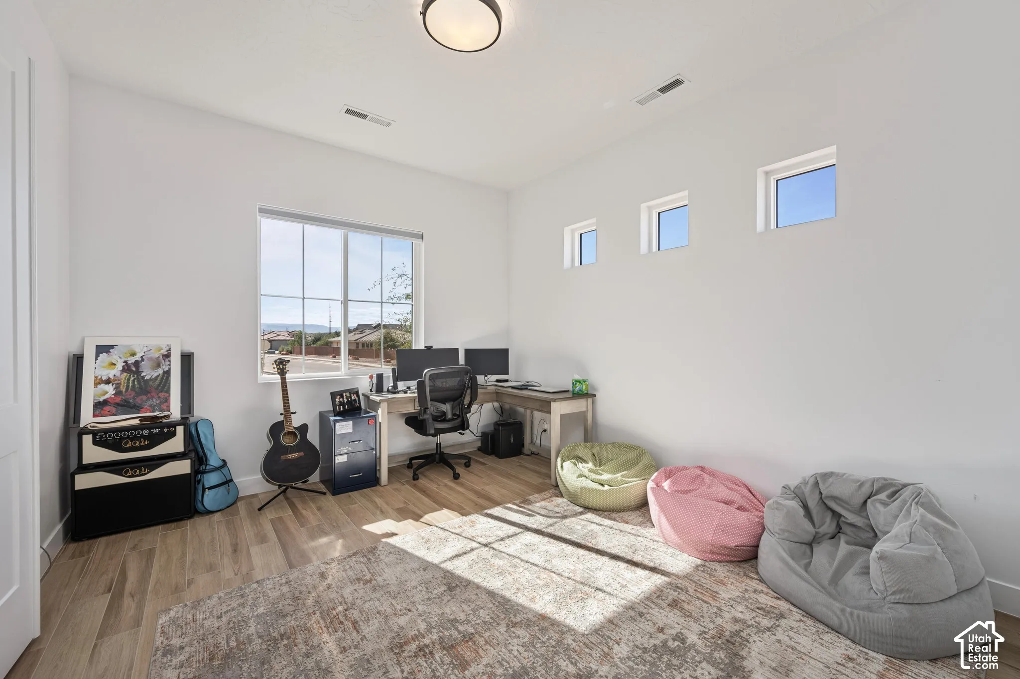 bed/office Room featuring wood-finish flooring, a large grid-pattern window, three high-set transom windows, and a flush-mount ceiling light