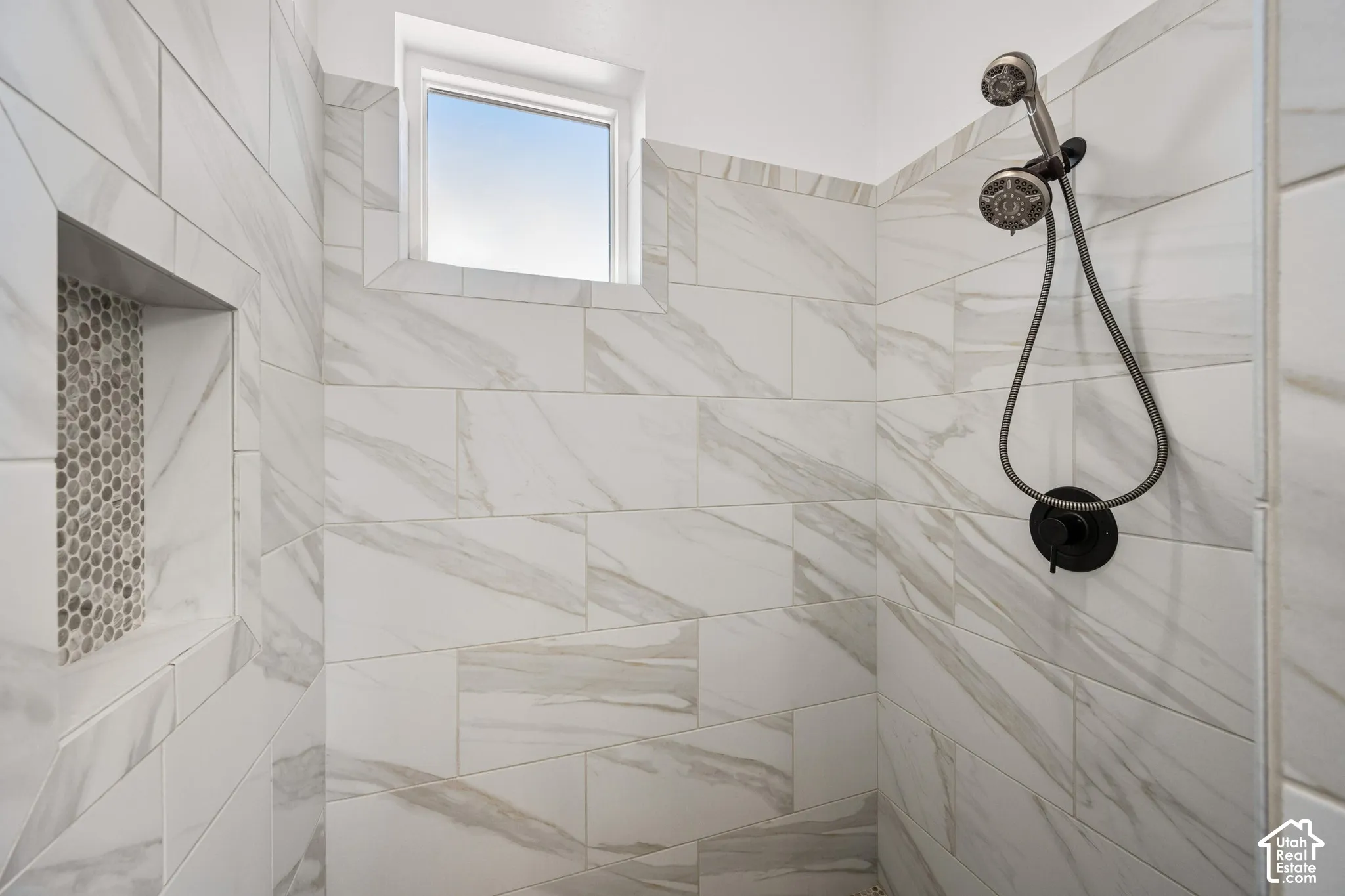 Primary Shower featuring rectified large-format tile walls, integrated recessed shelving with mosaic inlay, matte black hardware, and an adjustable handheld showerhead