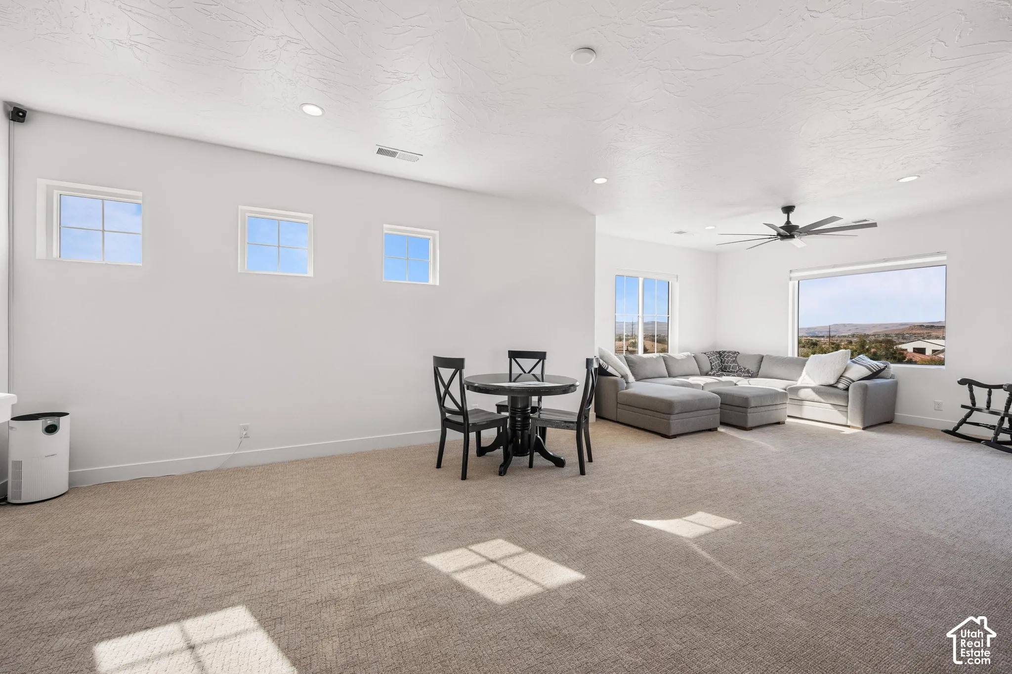 Open-concept space featuring neutral carpeting, recessed lighting, a modern ceiling fan, and large windows with mountain scenery