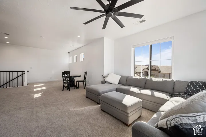 Expansive space featuring neutral wall-to-wall carpeting, a large multi-pane window, recessed lighting, and a modern matte black ceiling fan