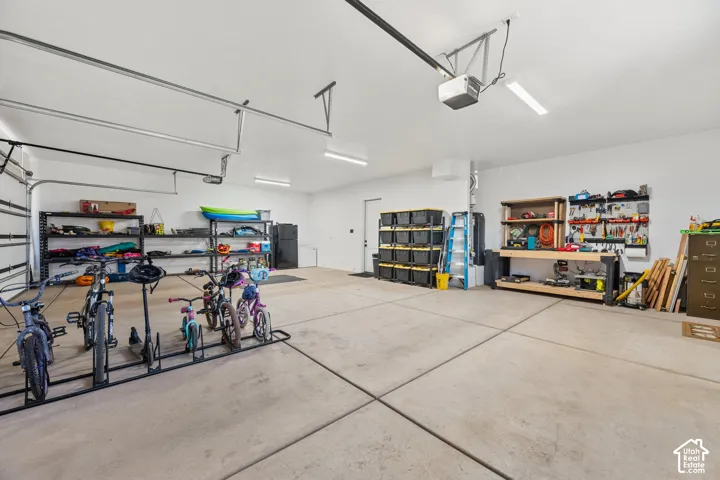 Multi-car garage featuring a concrete floor, high ceilings, automated door systems, and overhead LED lighting