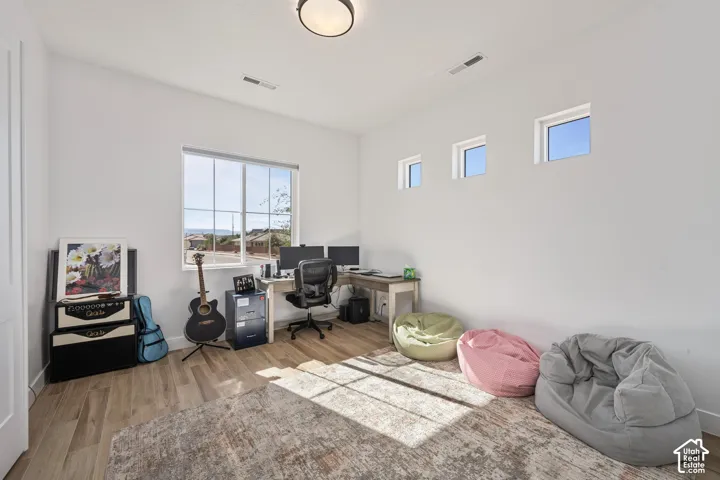 bed/office Room featuring wood-finish flooring, a large grid-pattern window, three high-set transom windows, and a flush-mount ceiling light