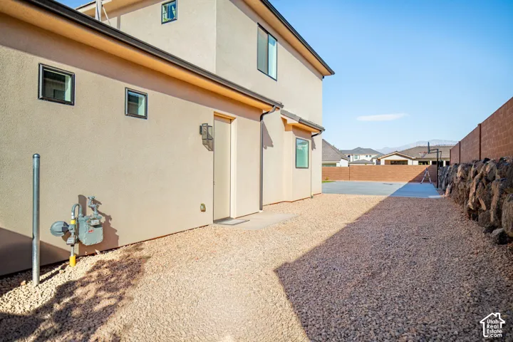Stucco exterior siding, low-maintenance gravel landscaping, concrete patio, and a stone retaining wall