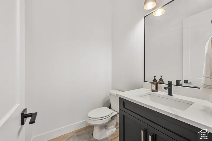 Dark-toned vanity with a rectangular sink, crisp white countertop, matte black faucet, and a large framed mirror with overhead lighting