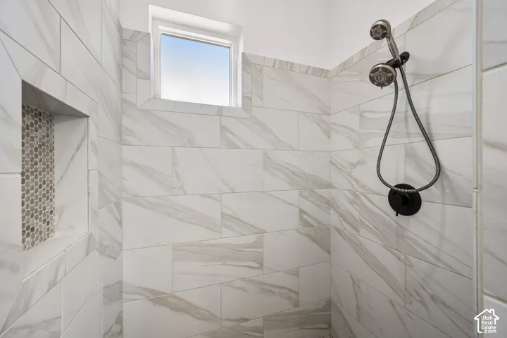 Primary Shower featuring rectified large-format tile walls, integrated recessed shelving with mosaic inlay, matte black hardware, and an adjustable handheld showerhead