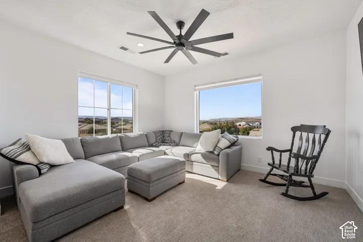 Neutral-toned interior featuring multi-pane windows, a large multi-blade ceiling fan, recessed lighting, and wall-to-wall carpeting