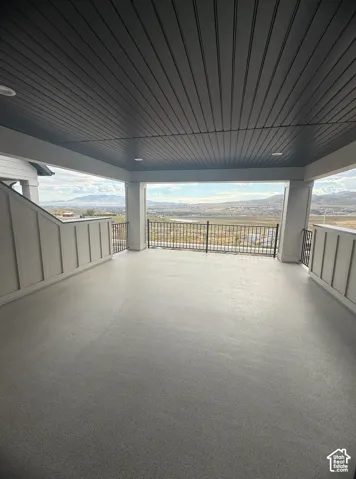 Covered balcony featuring board-and-batten siding, a dark tongue-and-groove ceiling, recessed lighting, and metal railings overlooking a mountain landscape
