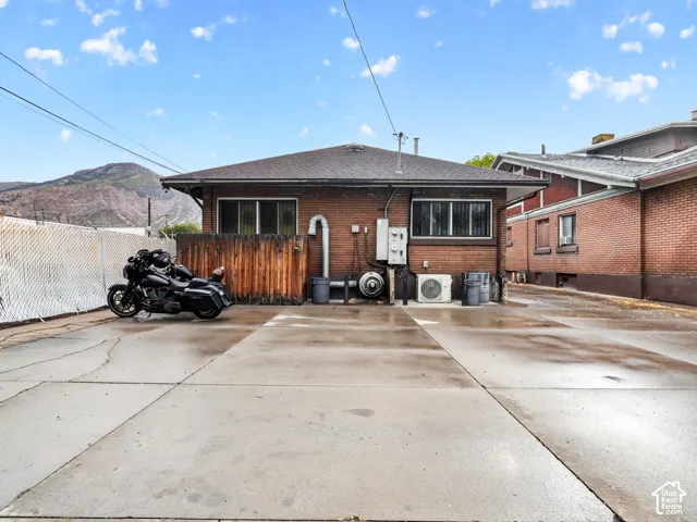 Brick exterior with a low-pitch roof, expansive concrete surface, and mountain backdrop